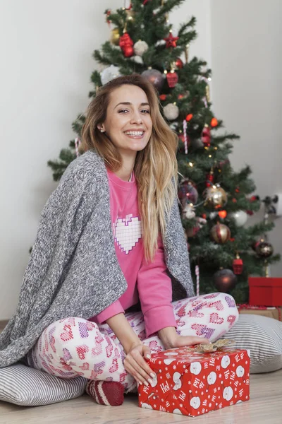 Mujer al lado de los regalos de apertura del árbol de Navidad —  Fotos de Stock