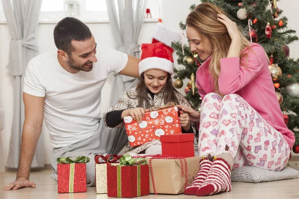 Family in front of Christmas tree opening presents — Stock Photo, Image