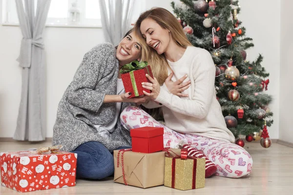 Женщины перед новогодней елкой открывают подарки — стоковое фото