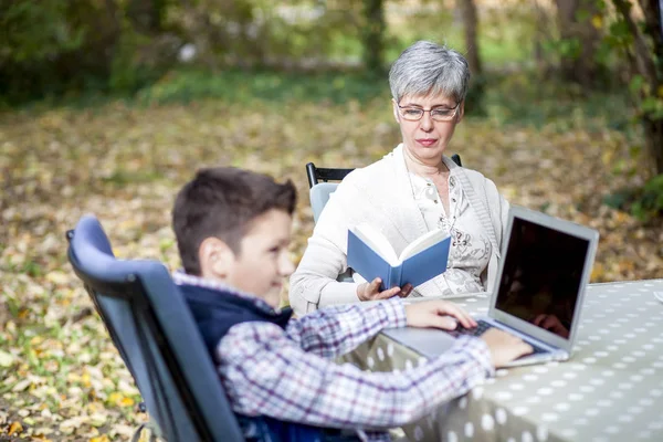 Женщина с внуком читают книгу, пьют кофе и разговаривают — стоковое фото