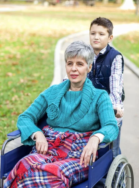 与祖母在轮椅上在公园的孙子 — 图库照片
