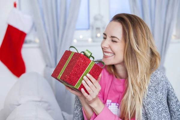 सोफा पर महिला एक क्रिसमस उपहार पकड़े हुए — स्टॉक फ़ोटो, इमेज