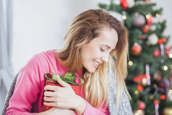 Žena na pohovce drží vánoční dárek — Stock fotografie