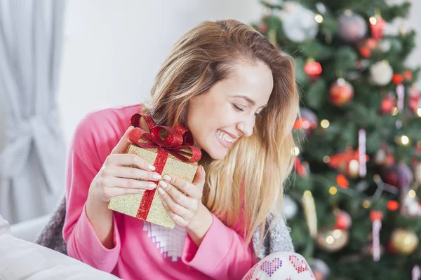 Woman on the sofa holding a Christmas present — Stock Photo, Image