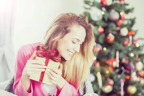 Mujer en el sofá sosteniendo un regalo de Navidad —  Fotos de Stock