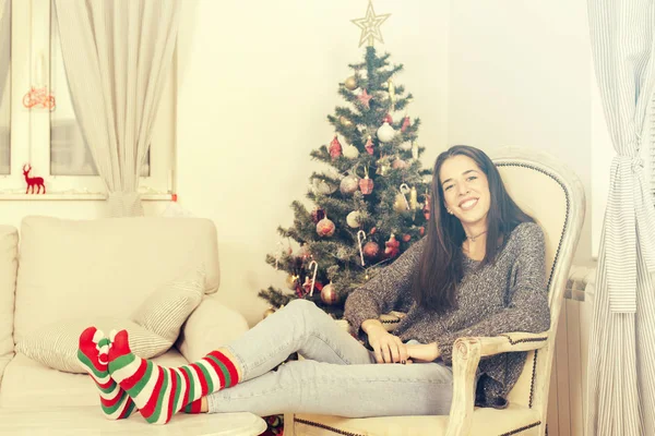 Noel ağacının yanındaki koltuk üzerinde oturan kadın — Stok fotoğraf