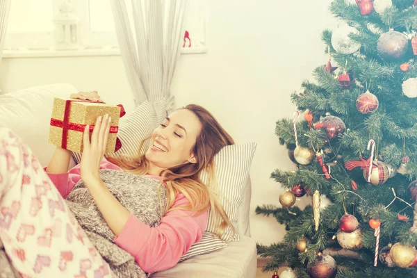Donna sdraiata sul divano con in mano un regalo di Natale — Foto Stock
