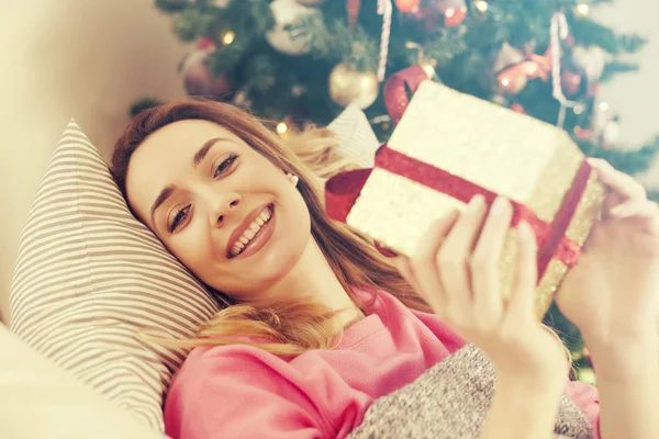 Femme couchée sur le canapé tenant un cadeau de Noël — Photo