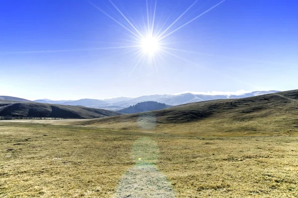 山の牧草地とその天頂の太陽の風景を見る — ストック写真