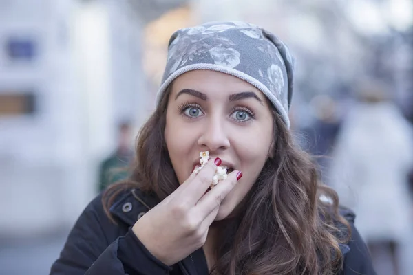 Молодая девушка ест попкорн во время прогулки по улице. портрет — стоковое фото