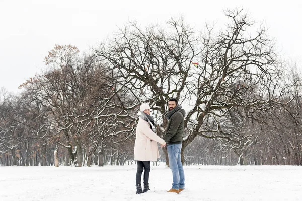 Любящая пара наслаждается снегом в парке — стоковое фото