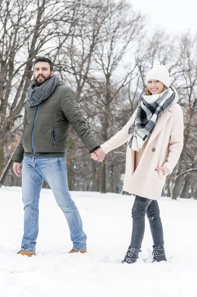 Casal amoroso curtindo a neve no parque — Fotografia de Stock