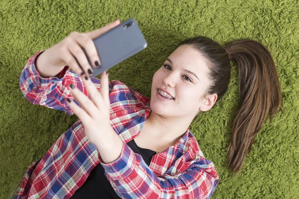 Adolescente tumbada en el suelo tomando selfie — Foto de Stock