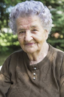 bahçede oturan mutlu yaşlı kadın