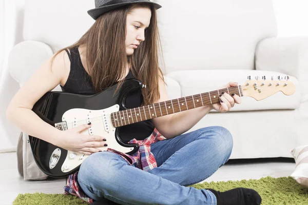 Tonårig flicka spela gitarr på golvet Stockbild