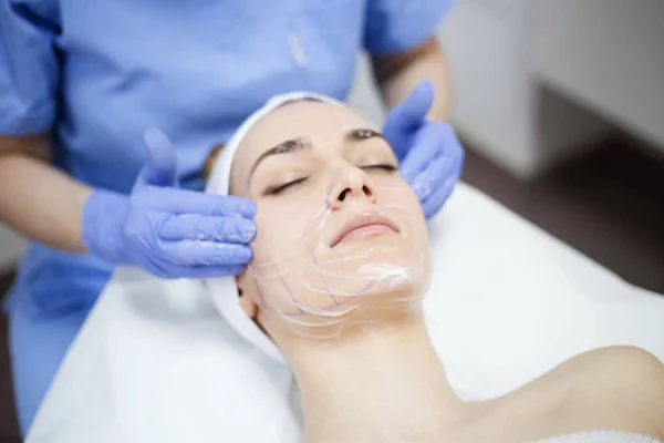 Woman at spa salon applying facial mask — Stock Photo, Image