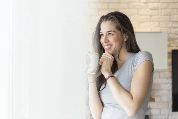 Woman enjoying coffee next to window