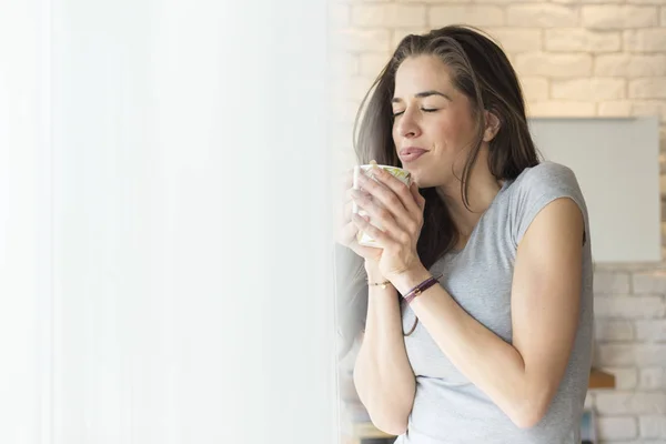 Woman enjoying coffee next to window