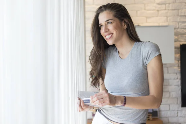 Mujer disfrutando de un libro junto a la ventana — Foto de Stock