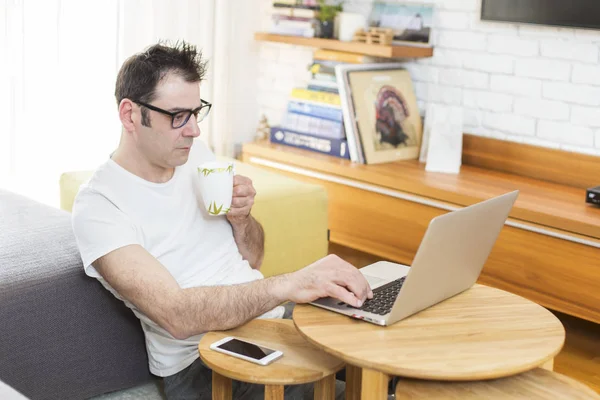 Людина у своїй вітальні працює на ноутбуці — стокове фото