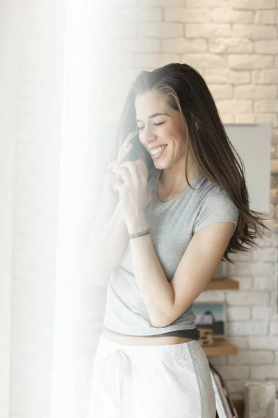 Утренняя сцена Женщина с сотовым телефоном рядом с окном — стоковое фото