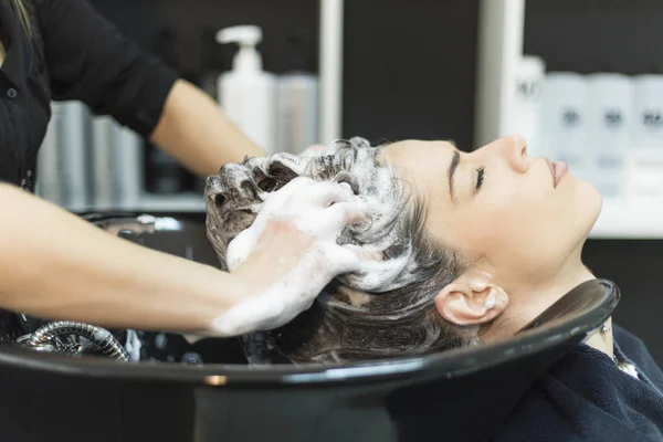 Beautiful young woman with hairdresser washing head at hair salo — Stock Photo, Image
