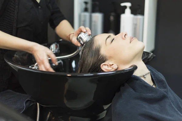 Beautiful young woman with hairdresser washing head at hair salo — Stock Photo, Image