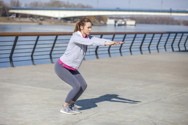 Ejercicio matutino junto al río. Una mujer joven en la recreación y — Foto de Stock