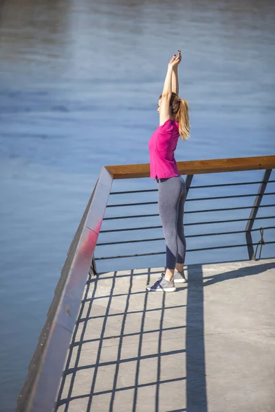 Morgengymnastik am Fluss. eine junge Frau auf Erholungsurlaub und — Stockfoto