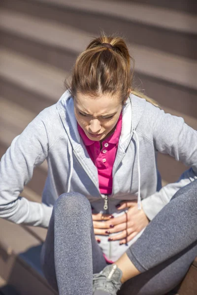 Woman with abdominal pain sitting on the steps — Stock Photo, Image