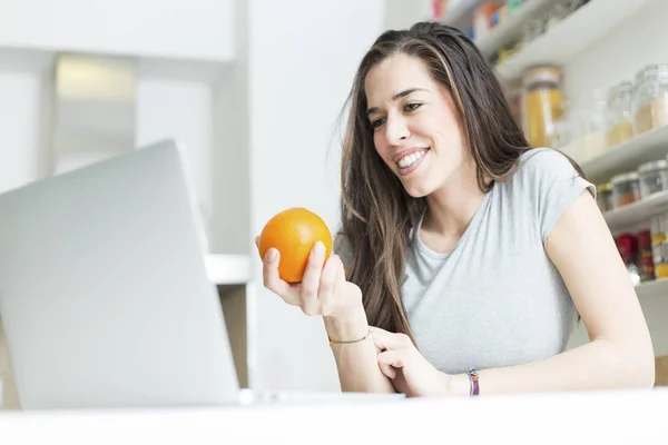 Утренняя сцена Красивая женщина держит оранжевый перед ноутбуком — стоковое фото