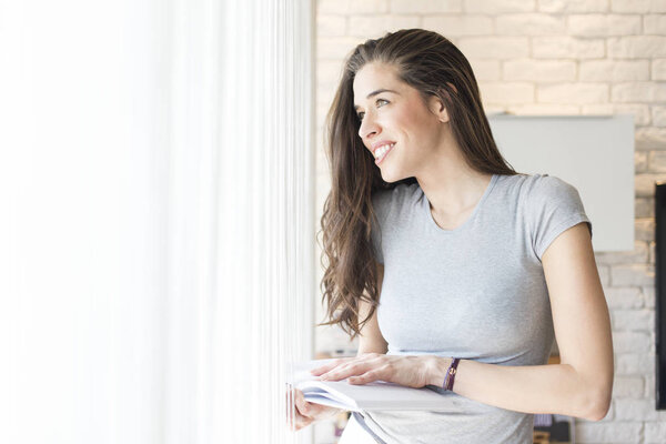 Morning scene. Woman enjoying a book next to window