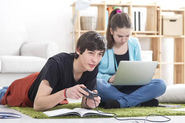 Zwei Teenager-Freunde. Junge spielt Spielkonsole, Mädchen arbeitet an Spielkonsole — Stockfoto