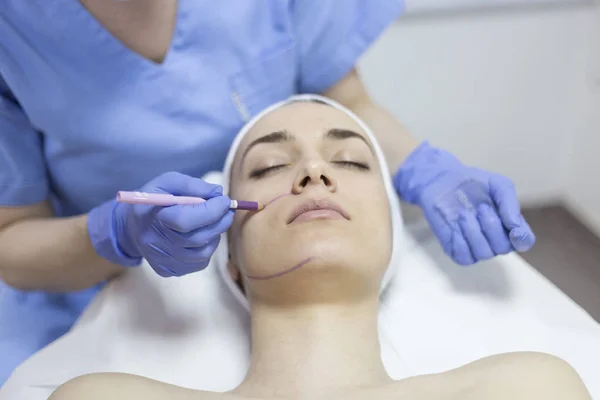 Beautician draw correction lines on woman face — Stock Photo, Image