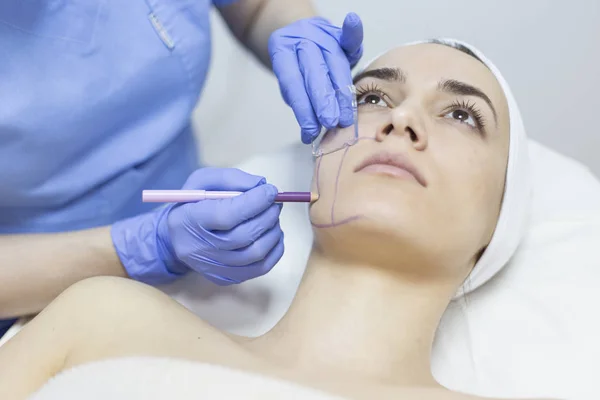 Estetista disegnare linee di correzione sul viso della donna — Foto Stock