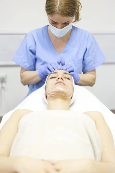 Cosmetico donna applicando maschera facciale — Foto Stock