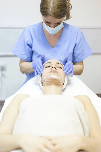 Kosmetikerin trägt Gesichtsmaske auf — Stockfoto