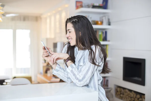 Ung kvinna med telefonen hemma — Stockfoto