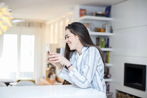 Jonge vrouw met telefoon thuis — Stockfoto