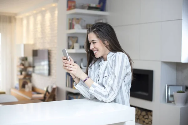 Jovem com telefone em casa — Fotografia de Stock