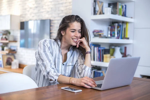 Ung kvinna som arbetar på laptop hemma — Stockfoto