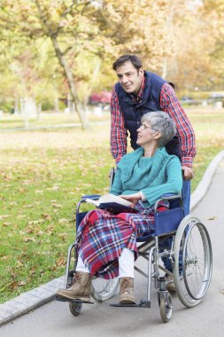  Bir tekerlekli sandalye ile oğlu arasında park yürüyüş kadında