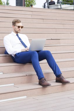 Dizüstü bilgisayarda çalışan yakışıklı genç işadamı