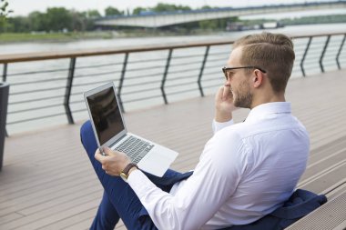 Dizüstü bilgisayarda çalışan yakışıklı genç işadamı