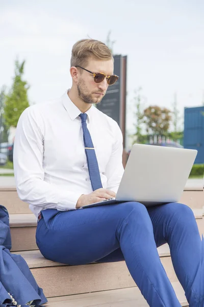 Knappe jonge zakenman die op laptop werkt — Stockfoto
