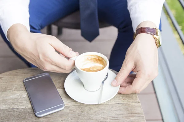 Üzletember kezében a csésze kávé és a telefon — Stock Fotó
