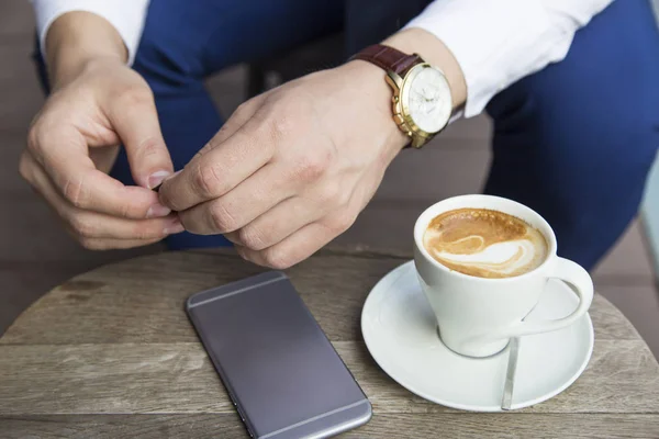 Руки бизнесмена с чашкой кофе и телефоном — стоковое фото