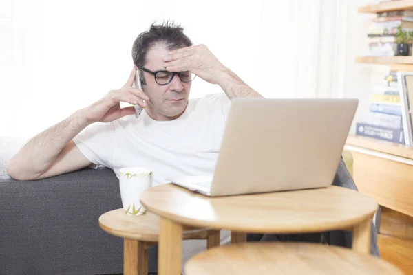 Boldogtalan hangsúlyozta ember előtt laptop a nappaliban — Stock Fotó