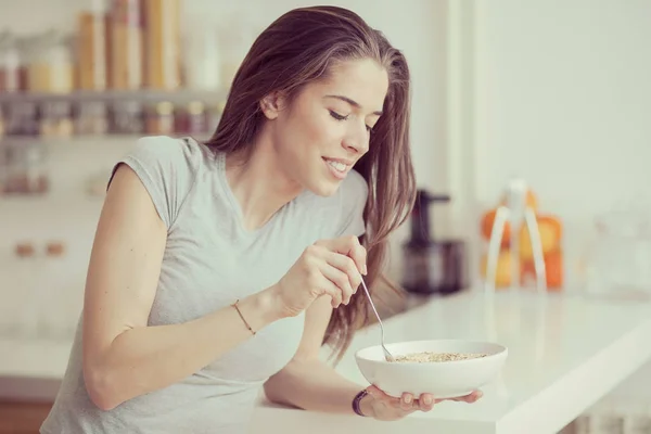 Mooie jonge vrouw handelscereals voor het ontbijt in de keuken — Stockfoto