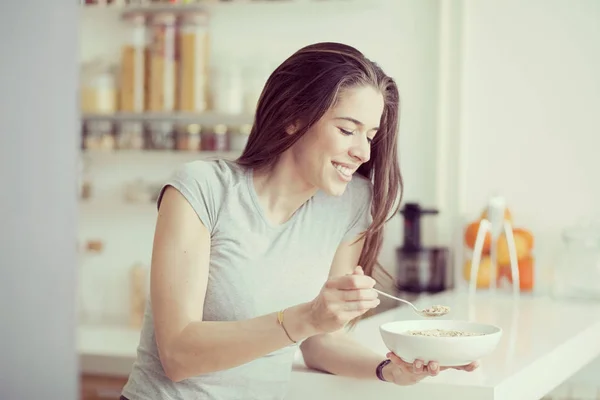 Mooie jonge vrouw handelscereals voor het ontbijt in de keuken — Stockfoto
